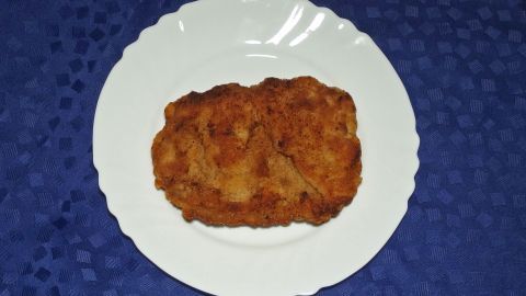 Ein panierter, knuspriger Snack liegt auf einem weißen Teller, umgeben von einem blauen Tischcloth.