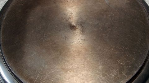 Eine stark verschmutzte Pfanne liegt auf einer Arbeitsfläche, bereit zur Reinigung mit einem Spülmaschinentab.