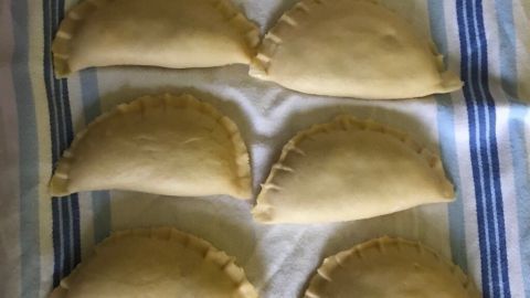 Feine Maultaschen liegen ordentlich auf einem gestreiften Tuch, bereit für die Zubereitung in Sahne/Käsesoße.