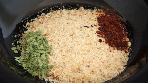 Leckere Panade aus Semmelbröseln, getrockneter Petersilie und fein geschnittenen getrockneten Tomaten. Eine Mischung aus Semmelbröseln und Gewürzen liegt in einer Schüssel, bereit zum Panieren von Fleisch und Fisch.