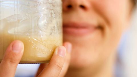 Trockene Lippen? Hier hilft Honig. Einfach etwas davon auf die Lippen auftragen, sie werden ganz zart. Ein lächelndes Gesicht hält ein Glas mit Honig in der Hand, um zu zeigen, wie er trockene Lippen pflegen kann.
