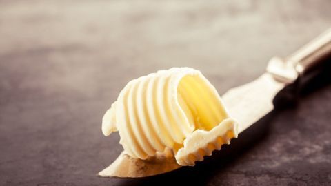 Ein Stück Butter liegt auf einem Messer, bereit zum Einsatz in der Küche, um Schmierflecken auf Kleidung zu bekämpfen.