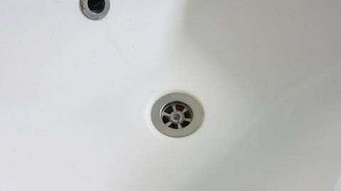 Ein strahlend weißes Waschbecken mit einem klaren Abfluss und einem unbenutzten Wasserhahn in einem modernen Badezimmer.