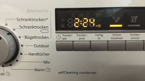 Ein Trockner mit digitaler Anzeige läuft, um Wäsche zu trocknen, während die Uhrzeit auf 82 Minuten eingestellt ist.