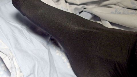 Eine schwarze Nylonsocke liegt auf einem hellen Stoff, um kalte und nasse Füße warm und geruchsneutral zu halten.