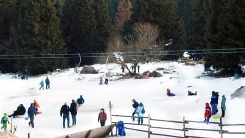 Kinder spielen fröhlich im Schnee, während sie warme Schuhe tragen, um sich bei Wind und Wetter draußen zu bewegen.