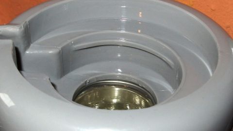 Eine graue Thermoskanne mit einem glänzenden Innenbehälter steht auf einer Oberfläche und wird mit Wäschebleiche gereinigt.