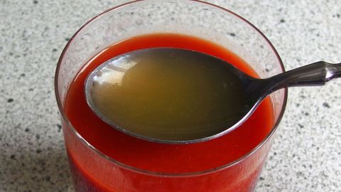 Etwas Apfelsaft macht Tomatensaft erst richtig intensiv und die Pektine des Apfelsaftes regen die Verdauung an. Ein Glas Tomatensaft hat einen Löffel Apfelsaft obenauf, beide Säfte sind getrennt sichtbar und stehen auf einer Arbeitsplatte.