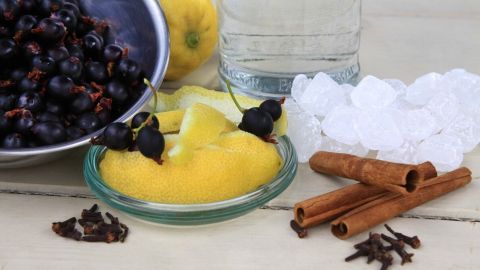 Schwarze Johannisbeeren werden neben Zitronen und Zimtstangen zur Herstellung von Jostalikör vorbereitet, umzugeben von Eis.