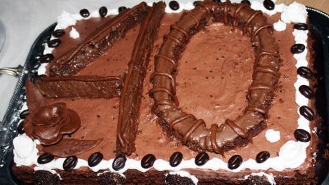 Schokoladenkuchen zeigt die Zahl "40", verziert mit Sahne und Schokoladenbohnen, auf silbernem Tablett serviert.