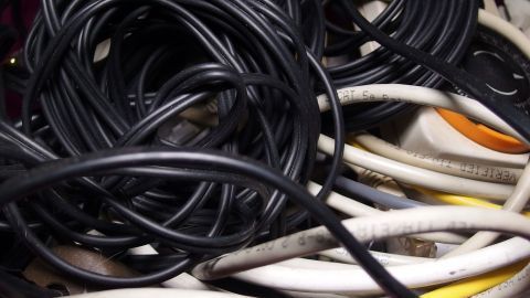 Verwirrte Kabel liegen ineinander verwoben in einem Behälter, was ein chaotisches Bild der Ordnung zeigt.