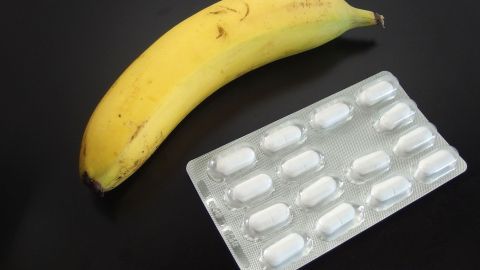 Eine Banane liegt neben einer Blisterpackung mit Tabletten, der Fokus liegt auf der Tabletteneinnahme im Vergleich zu Obst.