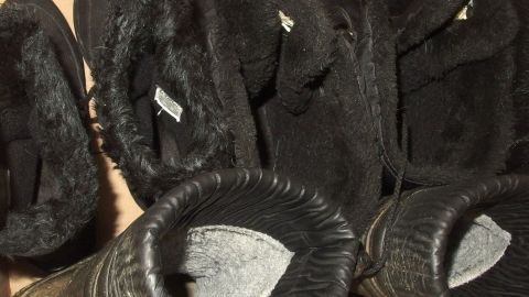 So herrscht mehr Ordnung im Schuhregal: Schuhe in Kartons aufbewahren und mit Foto versehen. Schwarze Hausschuhe liegen ordentlich nebeneinander auf einer Braune Pappe, bereit für den Gebrauch oder die Lagerung.