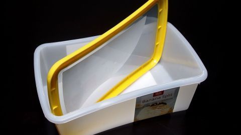 Ein stabiler Plastikbehälter mit gelbem Deckel steht auf einem schwarzen Hintergrund und zeigt die Möglichkeit zur Wiederverwendung.