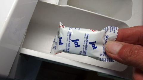 Ein Geschirrspültab wird in eine Waschmaschine gelegt, um schwierige Flecken zu entfernen. Der Tab ist verpackt.