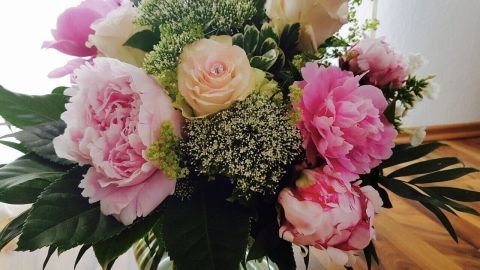 Ein bunter Strauß aus Schnittblumen steht in einer Vase, frisch arrangiert in einem hellen Raum.