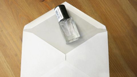 Ein Briefkuvert liegt auf einem Tisch, während eine Flasche Kleber die Klappe sicher verschließt.