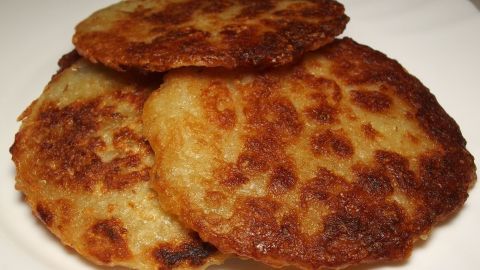 Kartoffelpuffer liegen auf einem Teller, goldbraun und knusprig, bereit zum Genießen in einer gemütlichen Küche.