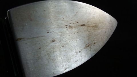 Ein gebrauchtes Bügeleisen hat eine stark verschmutzte Platte, die auf einem schwarzen Hintergrund liegt und gereinigt werden muss.