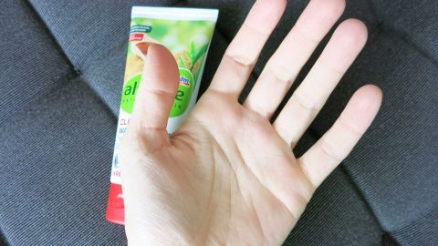 Eine offene Hand zeigt eine Creme gegen schwitzige Hände, die auf einem grauen Stoff liegt.