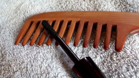 Ein Kamm und ein Applikator für Haaransatz kaschieren liegen auf einem Handtuch, bereit zum Verwenden für die Haarpflege.