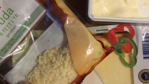 Eine Tüte mit Käseresten und einigen Zutaten liegt zusammen. Sie zeigt Käse für eine einfache Käsesoße in der Küche.