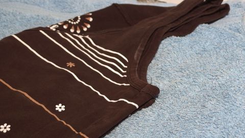 Ein dunkles T-Shirt liegt auf einem blauen Handtuch. Es zeigt getrocknete Deoflecken und benötigt eine Reinigung.
