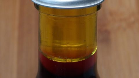 Eine Flasche mit mehrfarbigem Saft steht auf einem Holzuntergrund, bereit, ohne Einkochen haltbar gemacht zu werden.