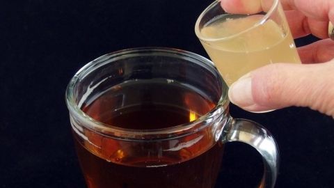 Ein Glas Tee wird mit einer kleinen Menge einer süßen Flüssigkeit gefüllt, um Tee ohne Zucker zu genießen.
