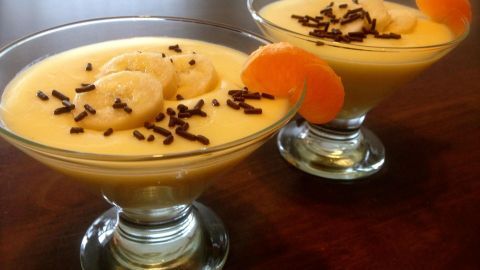 Cremiger Bananen-Vanille-Pudding in Schalen, garniert mit Bananenscheiben, Schokoladenspänen und Mandarinenstücken.