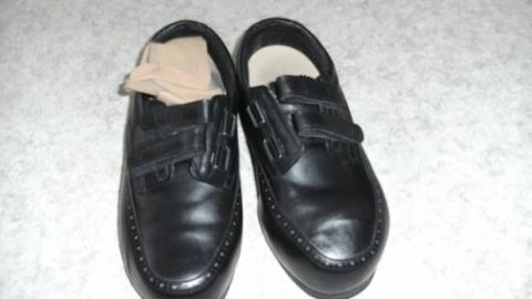 Verleihe deinen Schuhen neuen Glanz, indem du sie mit einem Nylonstrumpf polierst. Dieser einfache Trick aus dem Artikel hilft, den Glanz länger zu bewahren und kann als Alternative zu herkömmlichen Poliertüchern dienen. Schwarze Lederschuhe mit einem Nylonstrumpf in einem Schuh auf hellem Boden liegend.