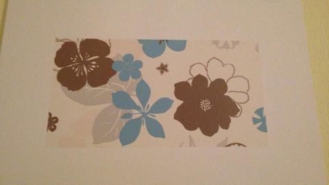 Eine Blütenillustration in Blau- und Brauntönen hängt an einer hellen Wand und verleiht der Wohnung lebendige Akzente.