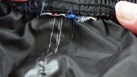 Ein Kleidungsstück mit Löchern wird repariert, während eine Hand den Stoff hält und den Bereich inspiziert.