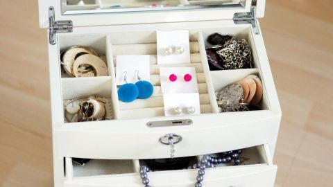 Ohrringe sind ordentlich in einer weißen Schmuckschatulle aufbewahrt, die mit mehreren Fächern ausgestattet ist.