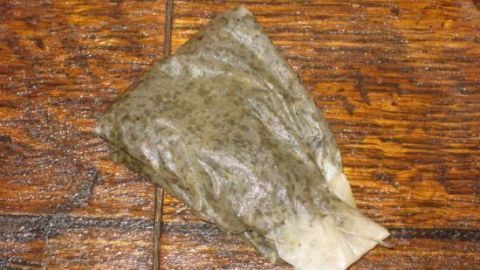 Ein Teebeutel liegt auf einer Holzoberfläche, während er darauf wartet, in Holzpolitur aus Schwarztee und Olivenöl verarbeitet zu werden.
