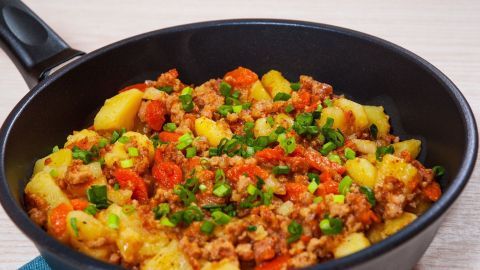 Ein Pfannengericht mit Fricco, das aus Hackfleisch, Gemüse und Kartoffeln besteht, auf einem hellen Tisch serviert.