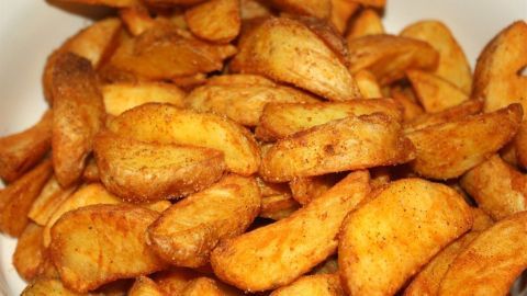 Knusprige Kartoffel-Wedges liegen in einer Schüssel und warten darauf, serviert zu werden. Sie sind goldbraun und appetitlich.
