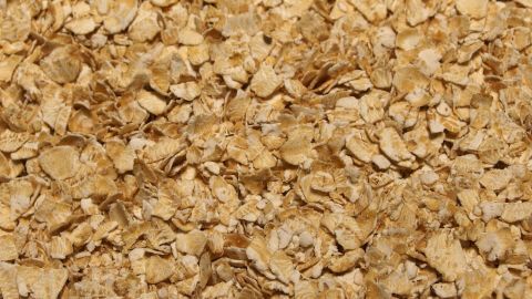 Vollkornhaferflockenpeeling mit Molke: Ein wunderbar schönes Peeling, das die Haut toll strahlen lässt. Vollkornhaferflocken liegen lose auf einer Oberfläche, bereit für die Verwendung in einem Peeling.