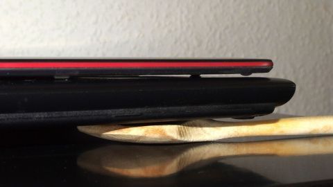 Ein schwarzes Notebook liegt auf einem Holzlöffel, wodurch die zusätzliche Kühlung beim Arbeiten ermöglicht wird.