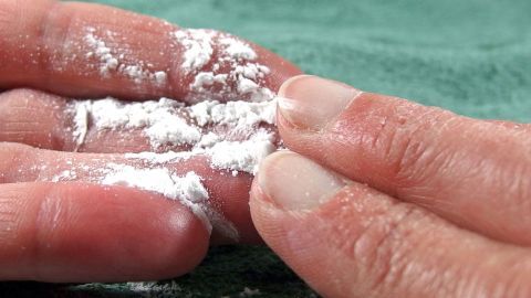 Hände mit Puder reinigen die klebrige Haut, um bei Hitze frisches Gefühl zu bewahren, auf einem grünen Tuch.