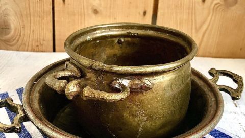 Kupfertöpfe stehen auf einem Tisch, während ein Reinigungstuch in der Nähe liegt, bereit zum Putzen.