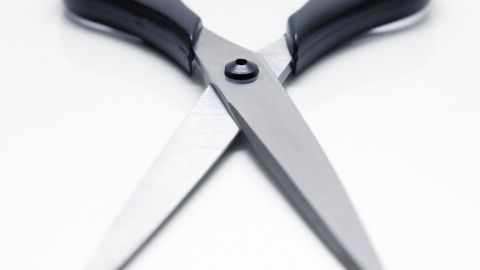 Eine Schere lässt sich mithilfe einer Weinflasche schleifen Eine Schere liegt auf einem weißen Tisch und ist geöffnet, bereit zum Schneiden von Papier oder Stoff für verschiedene Projekte.