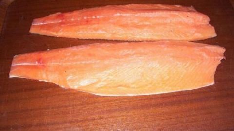 Lachsfilets liegen auf einem Holzbrett, bereit zum Beizen in der Küche.