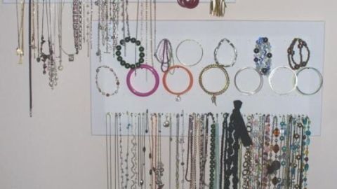 Ohrringe hängen an weißen Tafeln, ordentlich organisiert in einem Wohnbereich, mit Ketten und Armbändern darunter.