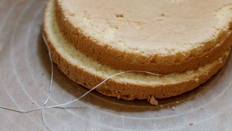 Mithilfe von Zahnseide prima Tortenböden schneiden. Funktioniert besser, als mit Bindfaden oder einem Messer. Eine Torte liegt auf einem Tisch, während Zahnseide verwendet wird, um die Schichten sauber zu trennen.