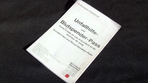 Ein Blutsender-Pass liegt auf einem dunklen Hintergrund und zeigt Informationen über Blutspenden und Erste Hilfe.