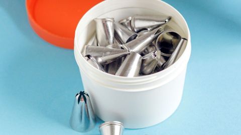 Bunte, runde Kunststoffdosen enthalten zahlreiche Metall-Tüllen, die zum Dekorieren von Backwaren verwendet werden.