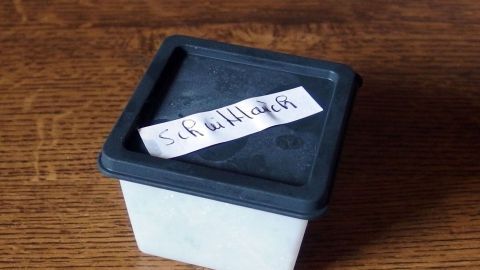 Gefrierdosen ganz einfach mit Papierstreifen kennzeichnen und beschriften. Eine Gefrierdose steht auf einem Holztisch und trägt ein handschriftliches Etikett zur Kennzeichnung des Inhalts.