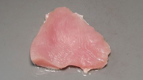 Zu bratendes Fleisch erst in das erhitzte Fett geben. Die Folge: Das Fett reicht für mehr "Bratgänge" und das Essen ist nicht ganz so fettreich. Ein Stück rohes Hühnerfleisch liegt auf einer flachen Oberfläche, bereit zum Braten in der Küche.