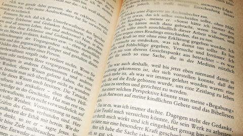 Ist ein Buch versehentlich nass geworden, kann man es in die Gefriertruhe legen, um ein Verkleben der Seiten zu verhindern. Ein aufgeschlagenes Buch zeigt verklebte Seiten, die Schwierigkeiten beim Lesen verursachen. Die Seiten wirken nass.